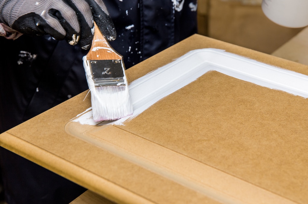 Repainting instead of replacing kitchen cabinet doors with white chalk paint indoors at home