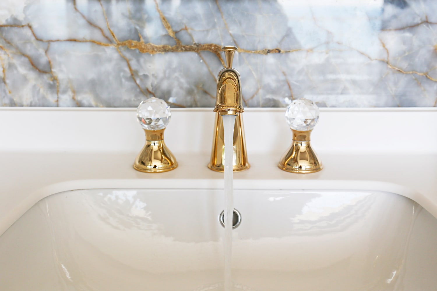 budget small bathroom remodel closeup view of running water from gold sink fixture